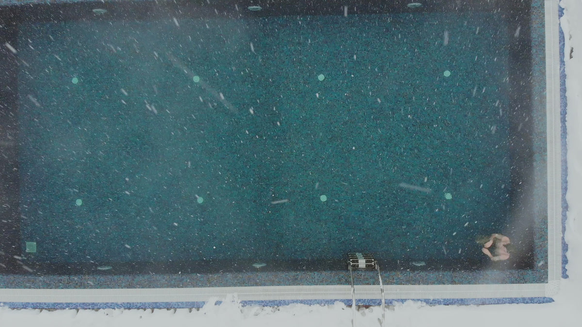 Snow falling on a swimming pool viewed from above